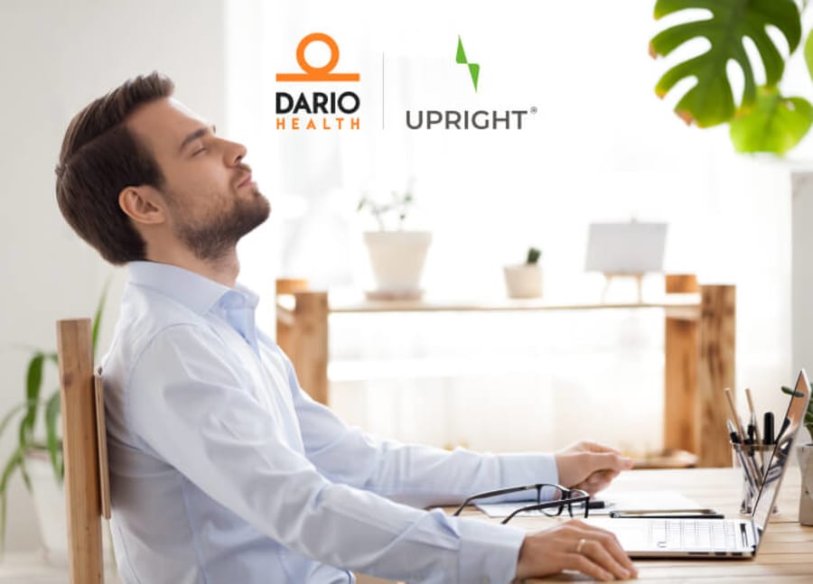 Man sitting back at desk looking relieved as he works