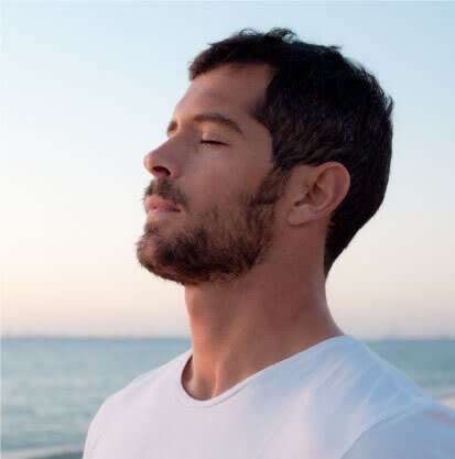 Man relaxing and closing his eyes at the beach