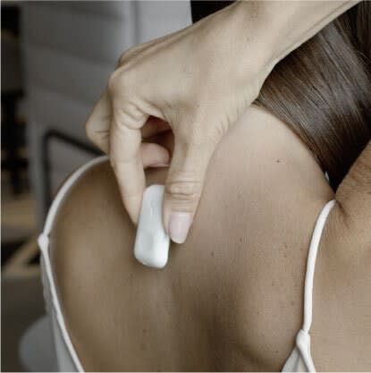 Woman placing the Upright Go device on her upper back