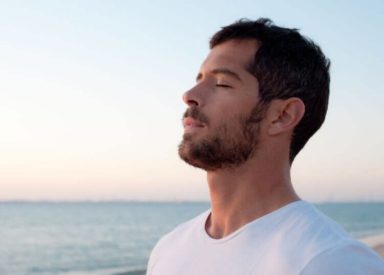 Man closing his eyes and relaxing at the beach