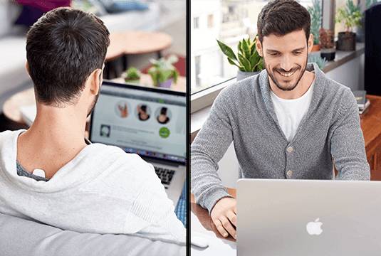 Young man with upright device on his back as he works on his laptop