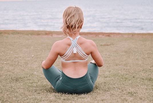 Woman with upright device on her back as she sits next to water