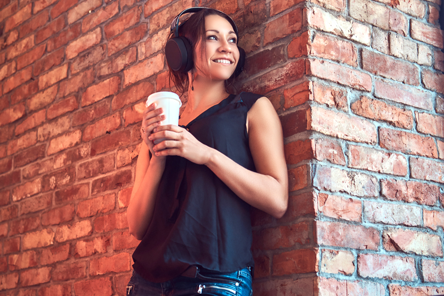 Woman standing with back against wall to improve singing posture.