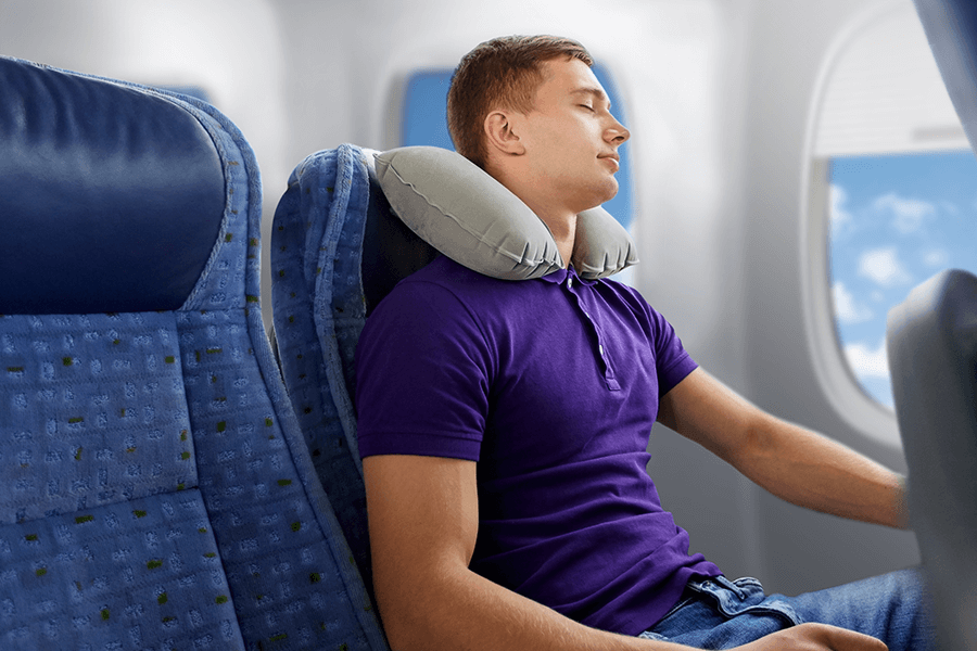 Sleeping male passenger with neck pillow, demonstrating correct travel posture.