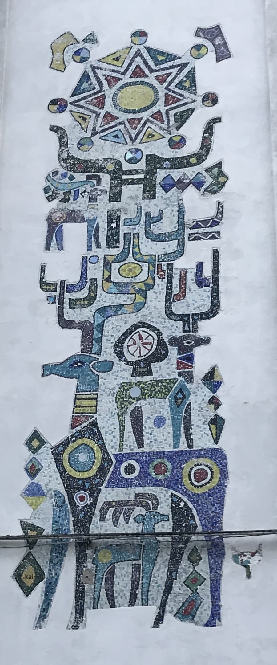 Ercüment Kalmık’ın 4. Levent’teki mozaik panosu: dikey, totem benzeri bir kompozisyon; üstte yıldız biçimli bir motif, altta boynuzlu bir hayvan figürü