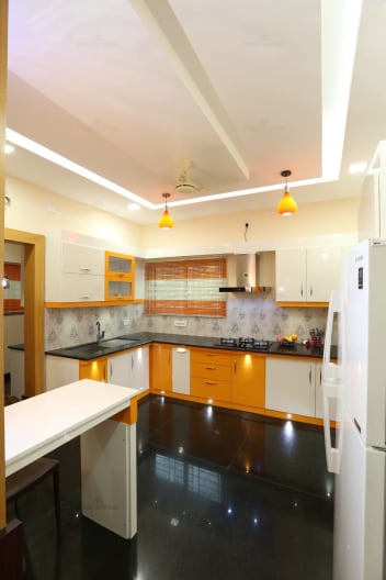 L Shaped Yellow And White Modular Kitchen With Black Marble