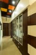 White hallway with wooden glass paneled display unit and multicolored fake ceiling by MakeMyCasa Indoor-spaces Modern | Interior Design Photos & Ideas