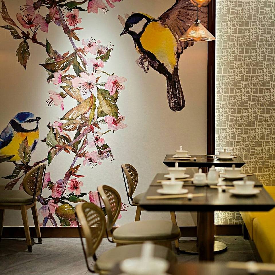 Restaurant With Wooden Table And Cushioned Chairs And Vibrant Wall Art by Nishtha Nayyar Modern | Interior Design Photos & Ideas