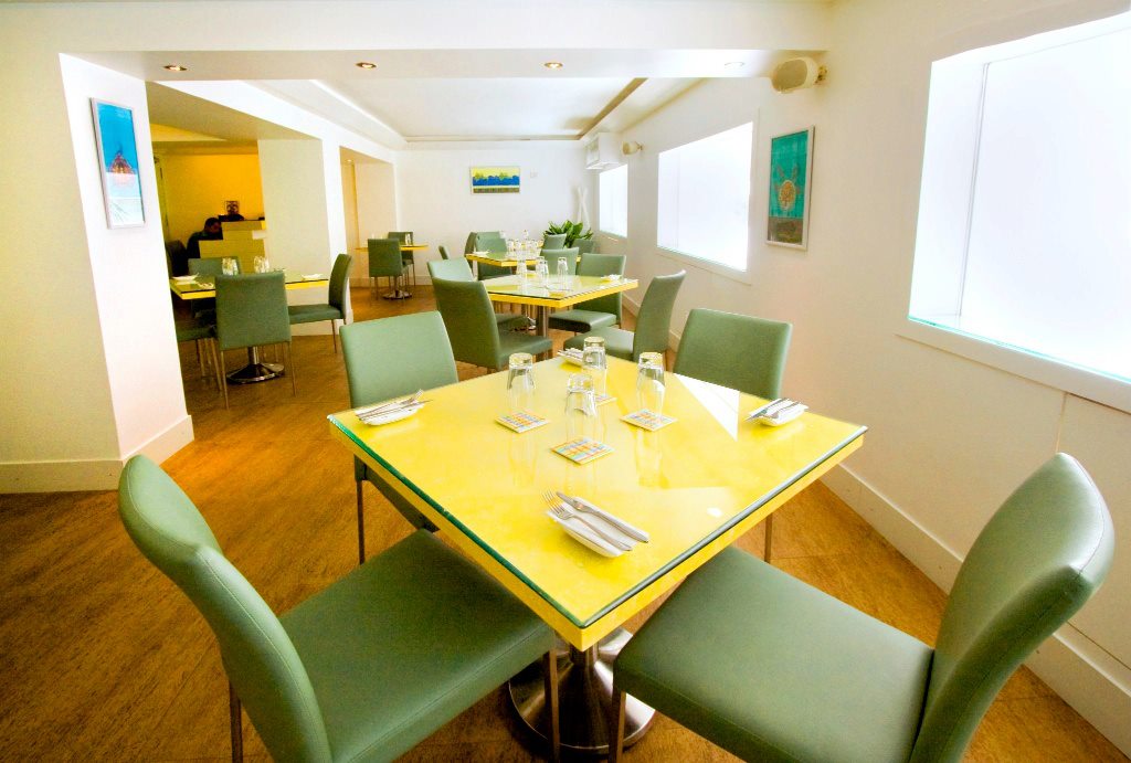 Colourful Restaurant With Sea Green Side Chairs and Lemon Yellow Glass Top Tables by Viraf Laskari Modern | Interior Design Photos & Ideas