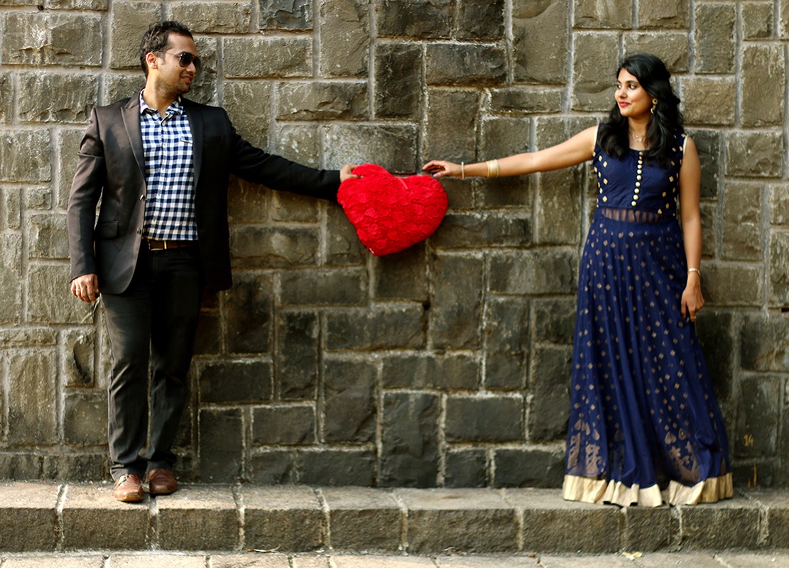 Bride and Groom To-Be Pose With a Red Heart-Shaped Pillow by Rushil Jadhav Wedding-photography Groom-wear-and-accessories Wedding-dresses | Weddings Photos & Ideas