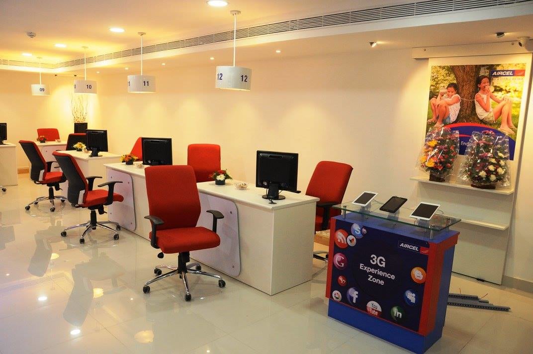 open office space with red chairs and white table by Ganesh