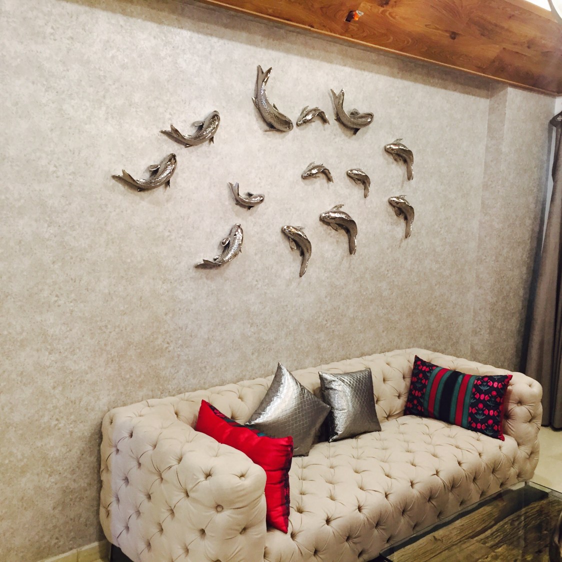 Beige themed living room with a chic design, vibrant colors displayed via pillows and shiny jumping fish wall display by Chaitanya Challa Living-room Modern | Interior Design Photos & Ideas