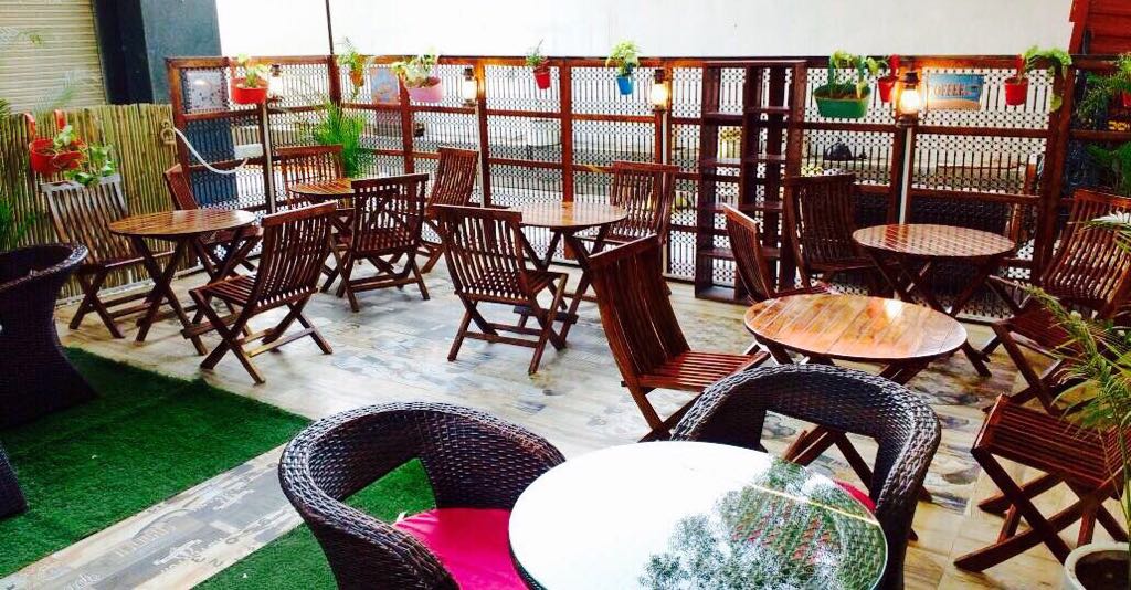 Open coffee shop with wooden backrest chairs and vibrant upholstery by Vikas Swami Contemporary | Interior Design Photos & Ideas