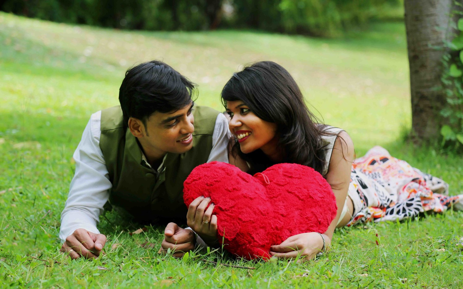 Bride and Groom To-Be Pose With a Heart Shaped Pillow Against a Picturesque Garden Background by Rushil Jadhav Wedding-photography | Weddings Photos & Ideas
