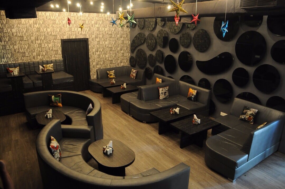 Top View of Dark Themed Restaurant with Round and L Shaped Sectional Sofa set by Rohit Mangal Singla Modern | Interior Design Photos & Ideas
