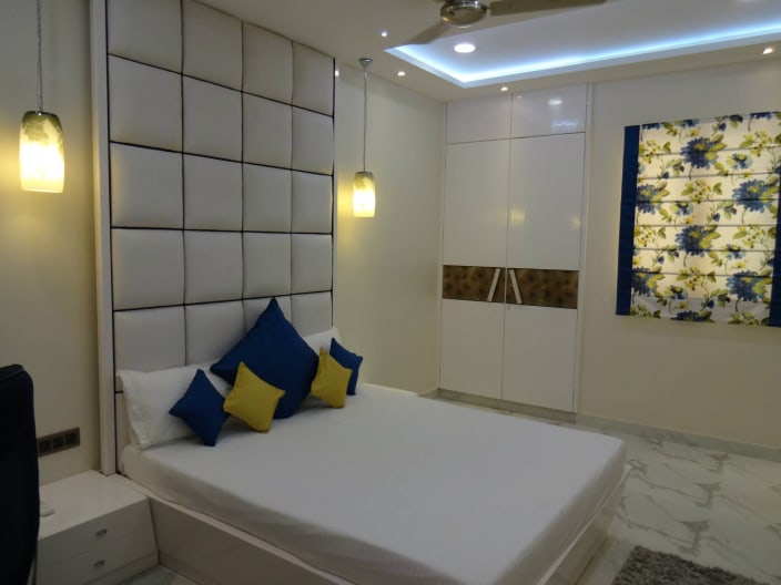 Sophisticated Master Bedroom With White Cushioned Back Wall By Sarita Sharma