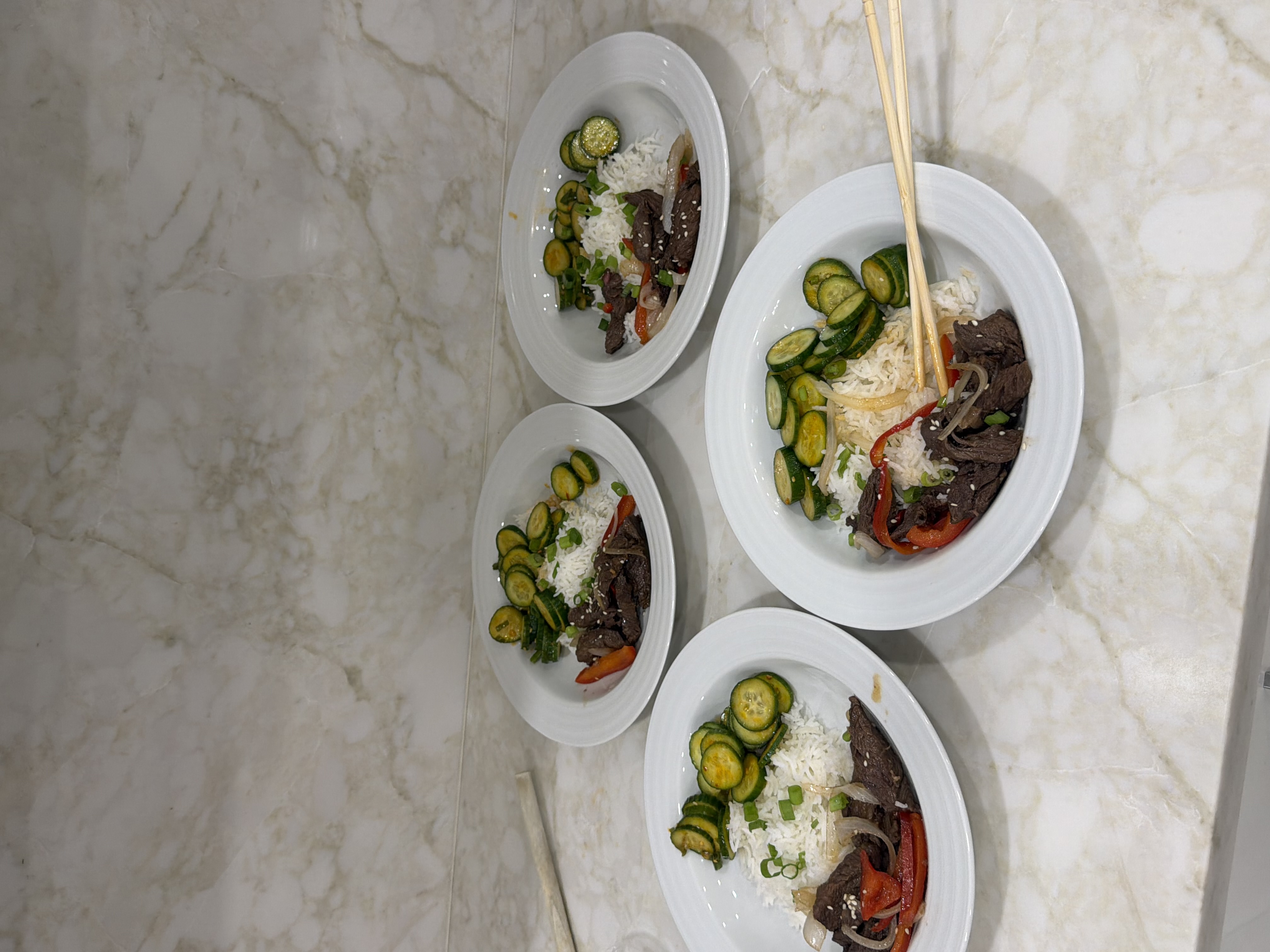 skirt steak with peppers and onions served over jasmine rice with a cucumber chili crisp salad