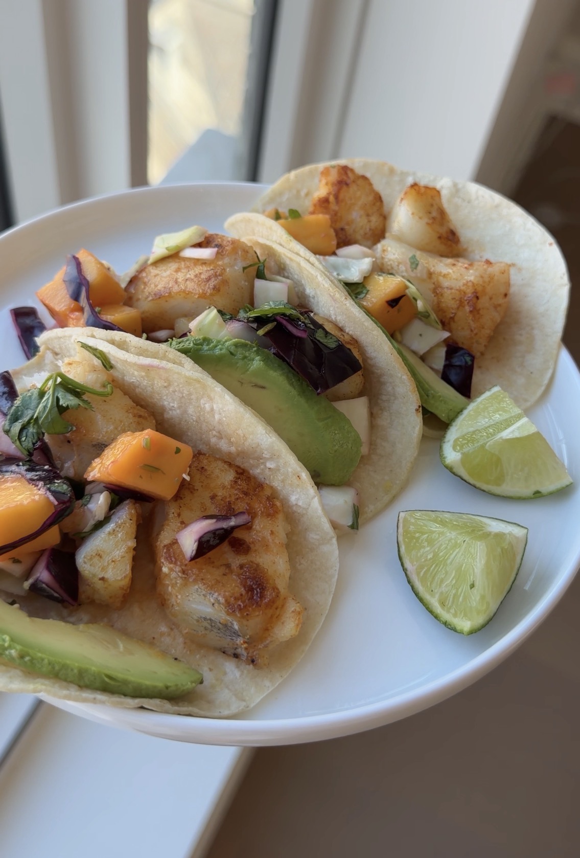 pan-seared cod tacos with mango cabbage slaw, avocado, and cilantro