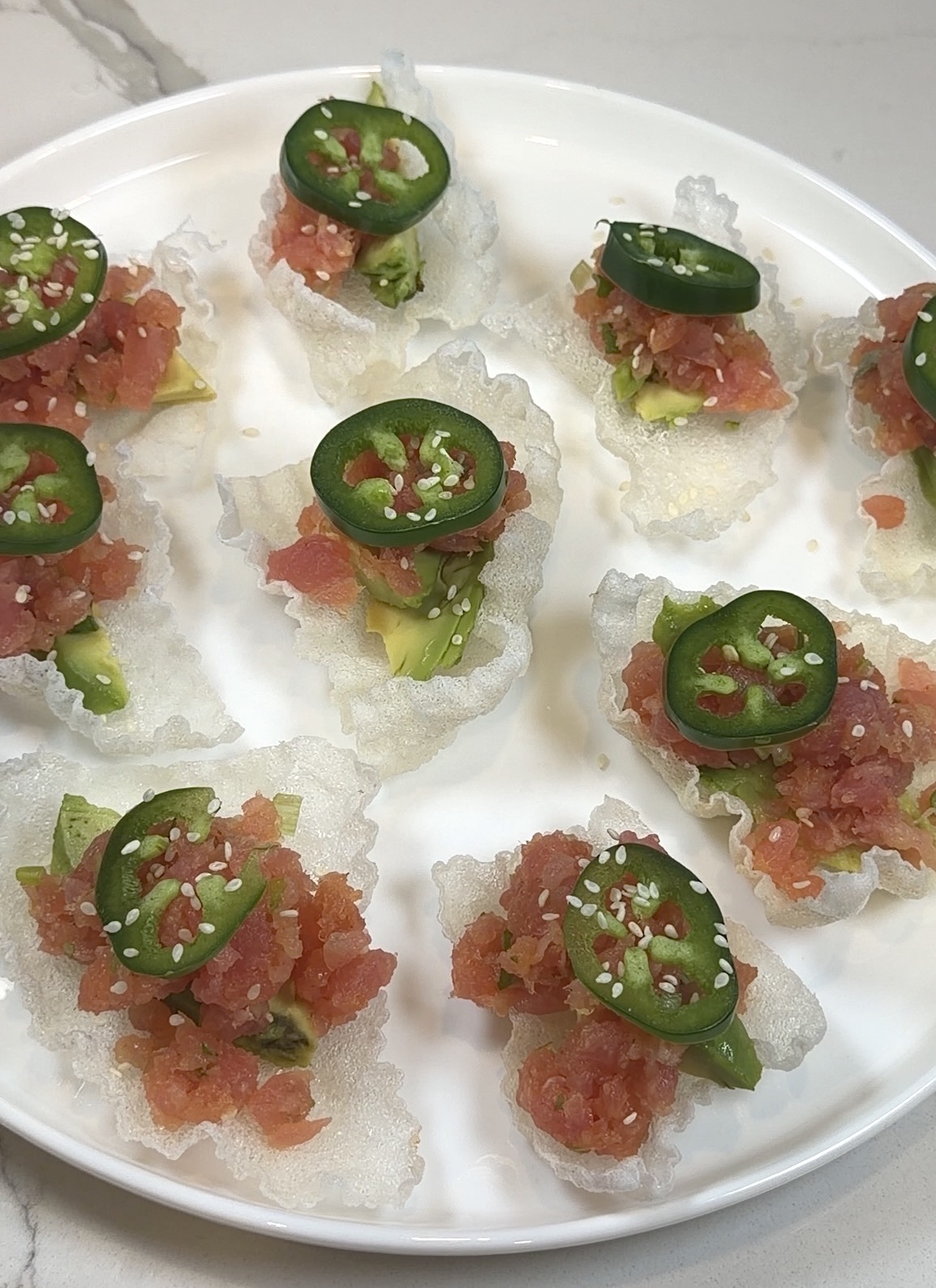 crispy rice paper bites topped with spicy tuna, avocado, jalapeño, green onion, and sesame seeds
