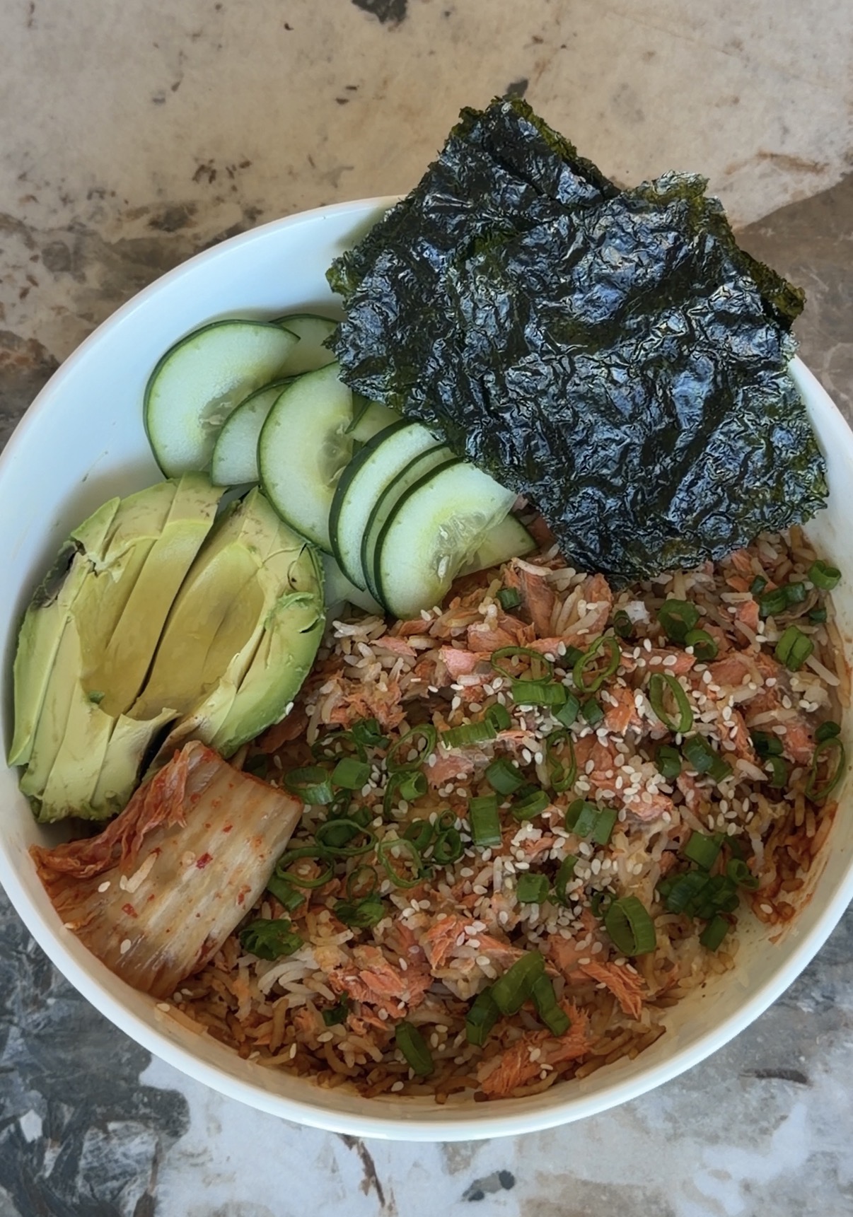 salmon rice bowl with avocado, cucumber, kimchi, green onions, and seaweed