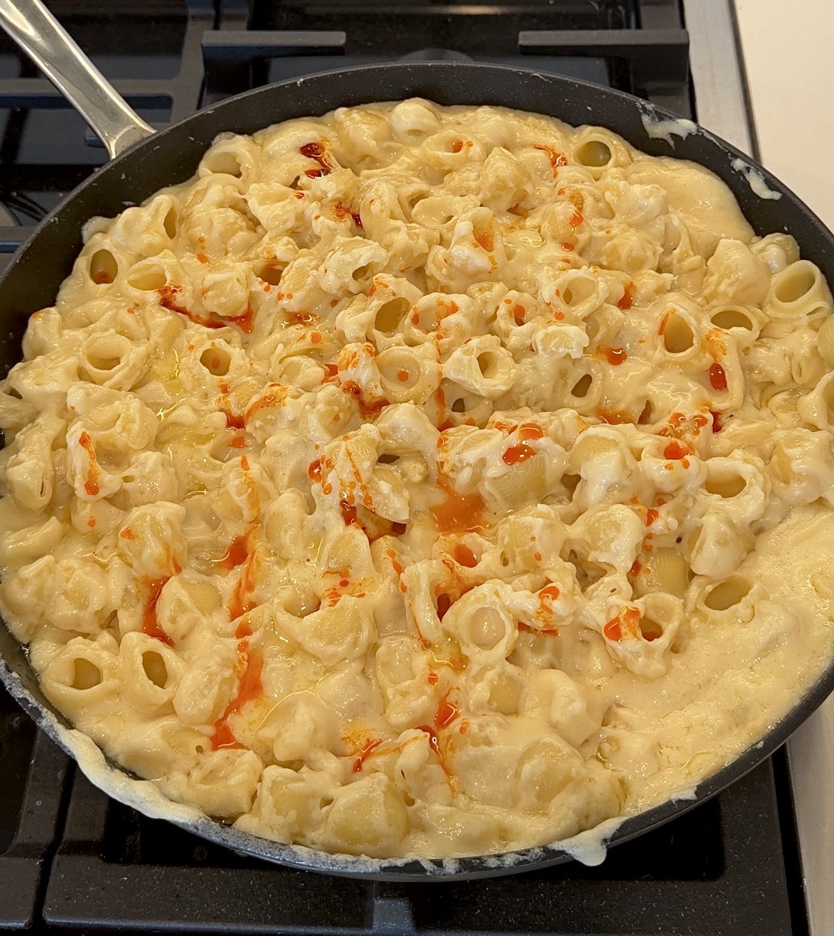 creamy white cheddar mac and cheese topped with chili crisp and sliced scallions