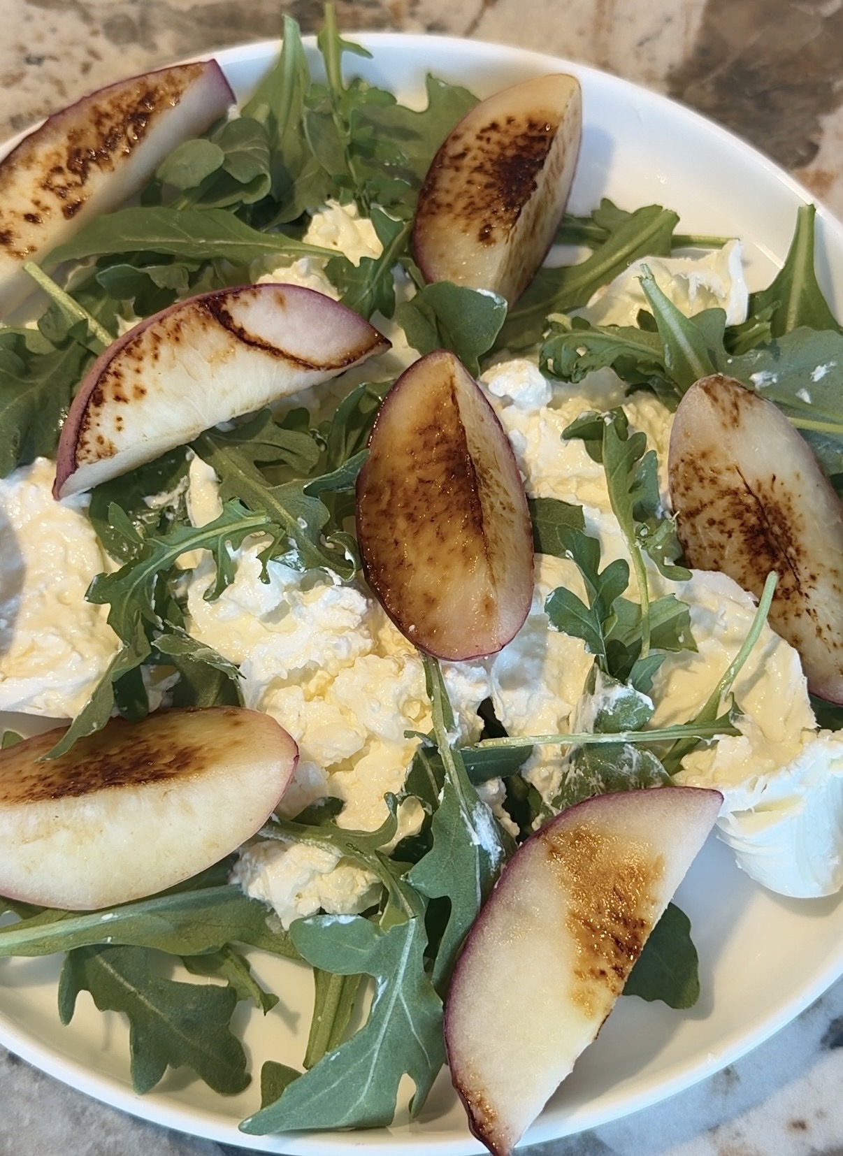 grilled peach and arugula salad with burrata, honey, and freshly cracked black pepper