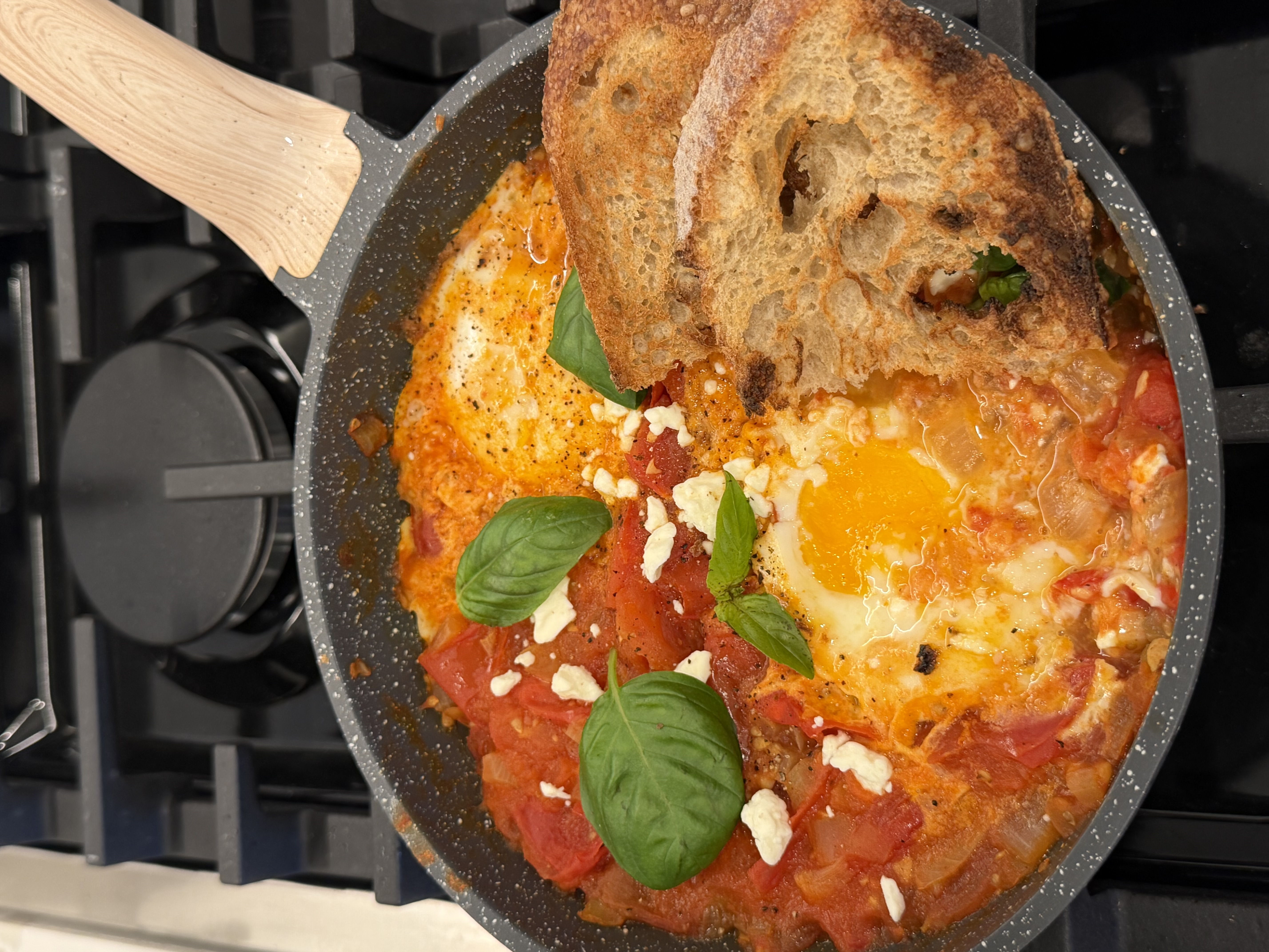 shakshuka with eggs poached in fresh tomato sauce and topped with feta and basil
