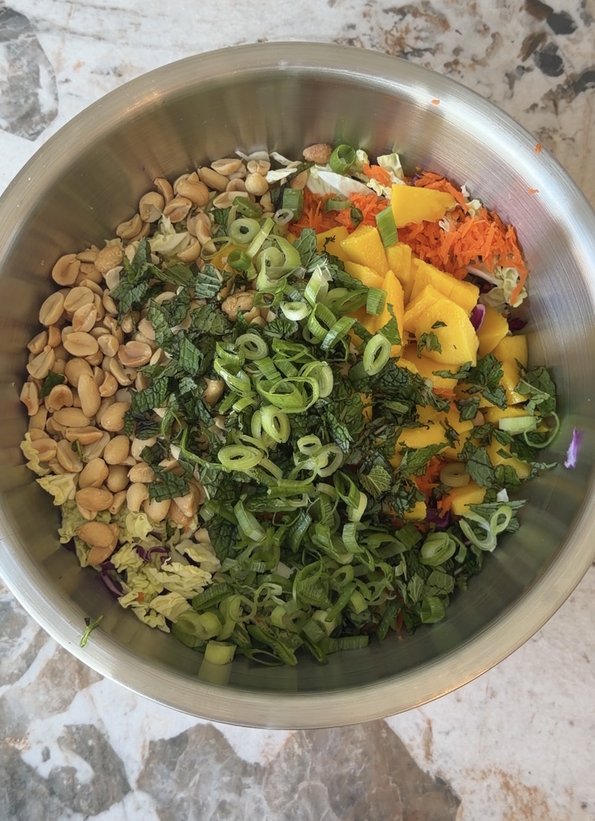 thai-style crunch salad with purple and green cabbage, mango, carrots, peanuts, mint, and scallions