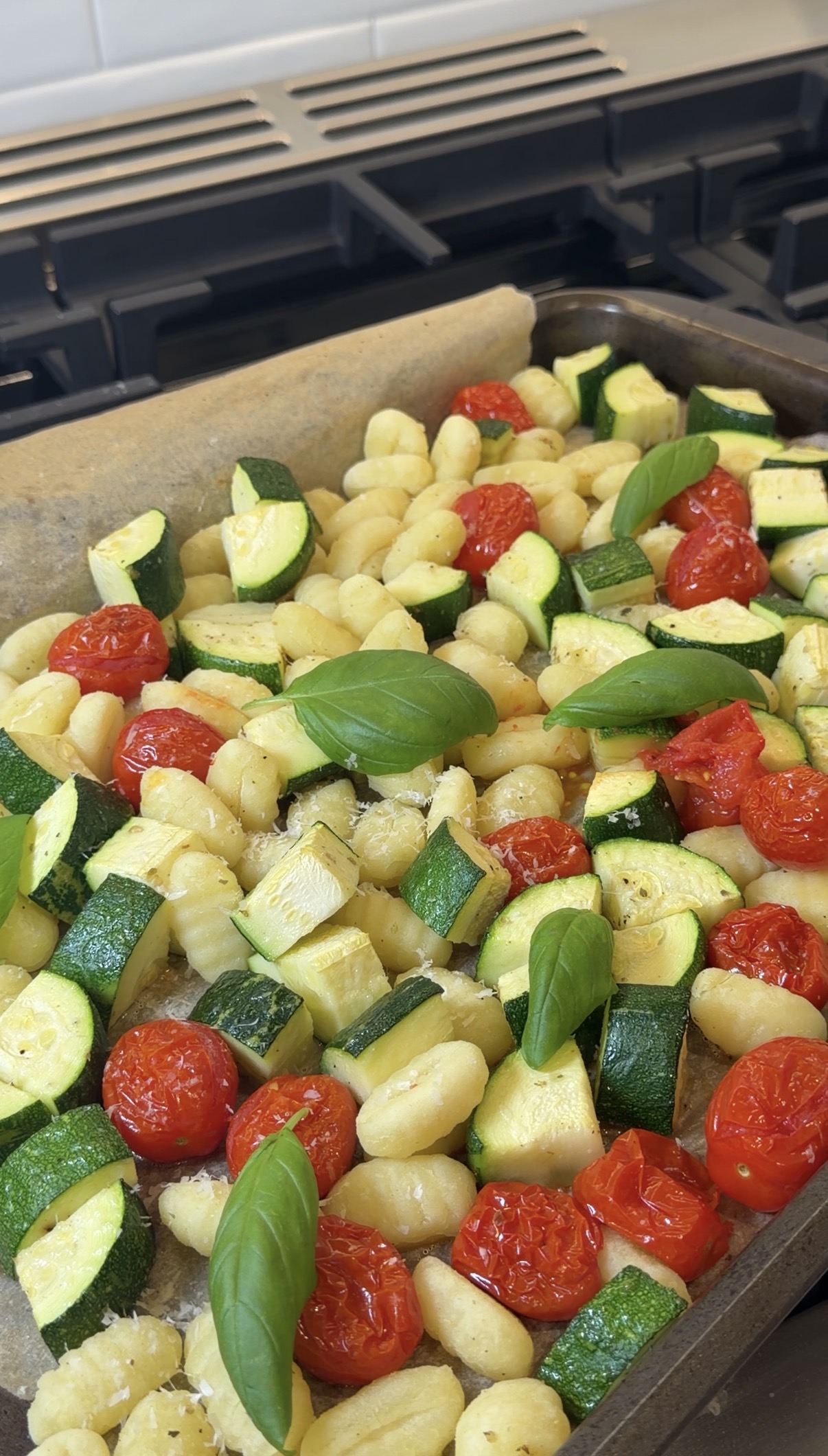sheet-pan gnocchi with roasted zucchini and grape tomatoes topped with parmesan and fresh basil