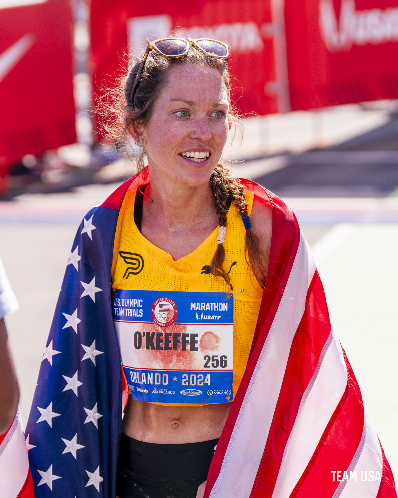 Fiona O'Keeffe smiles while draped in the American flag after winning 2024 US Olympic Marathon Team Trials in Orlando, Florida.