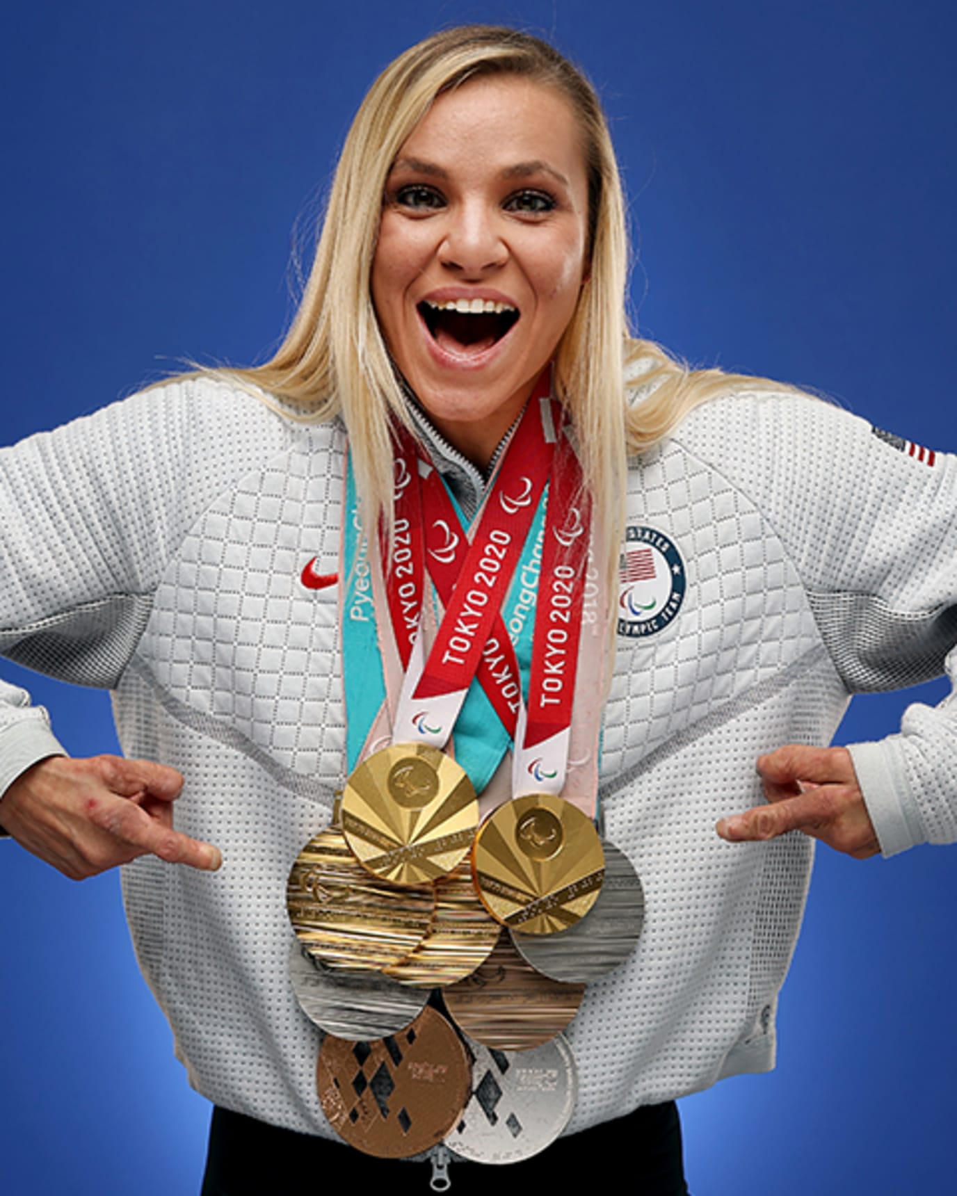 Oksana Masters smiles and points to her nine metals around her neck