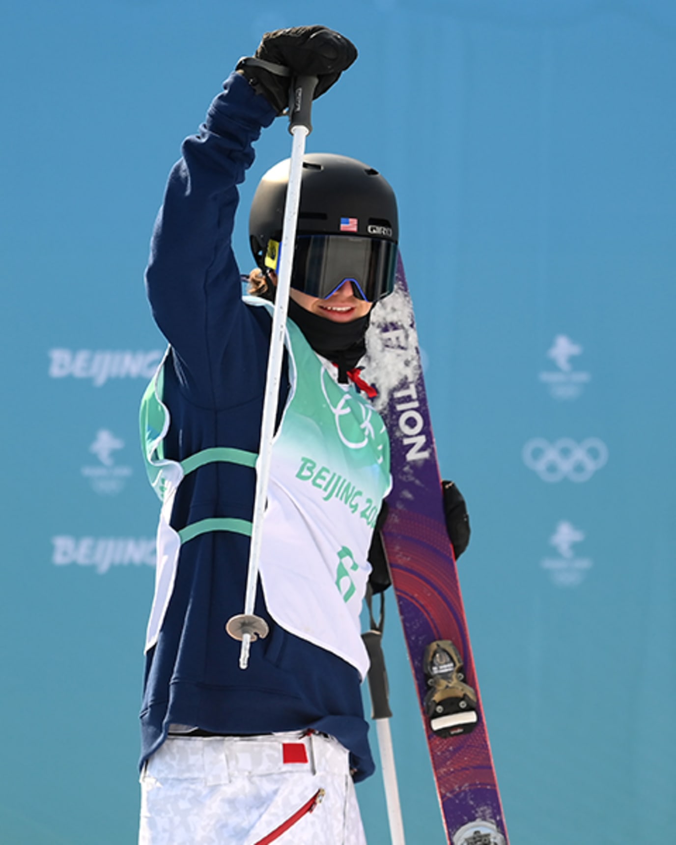 Mac Forehand gestures toward the camera while holding skis