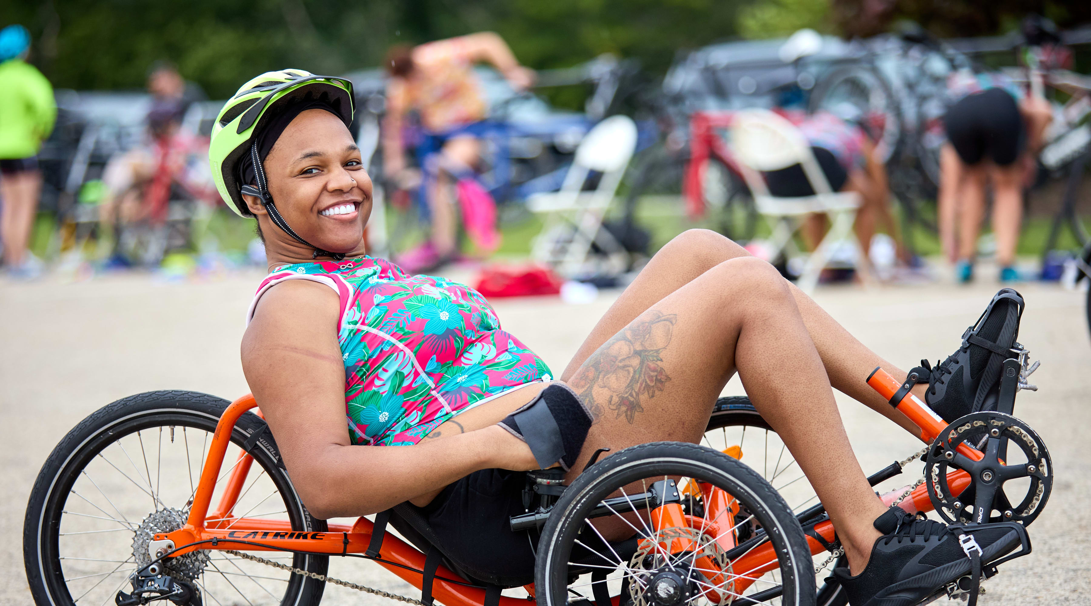 An athlete smiles and poses for a photo while sitting in a her recumbent bike.