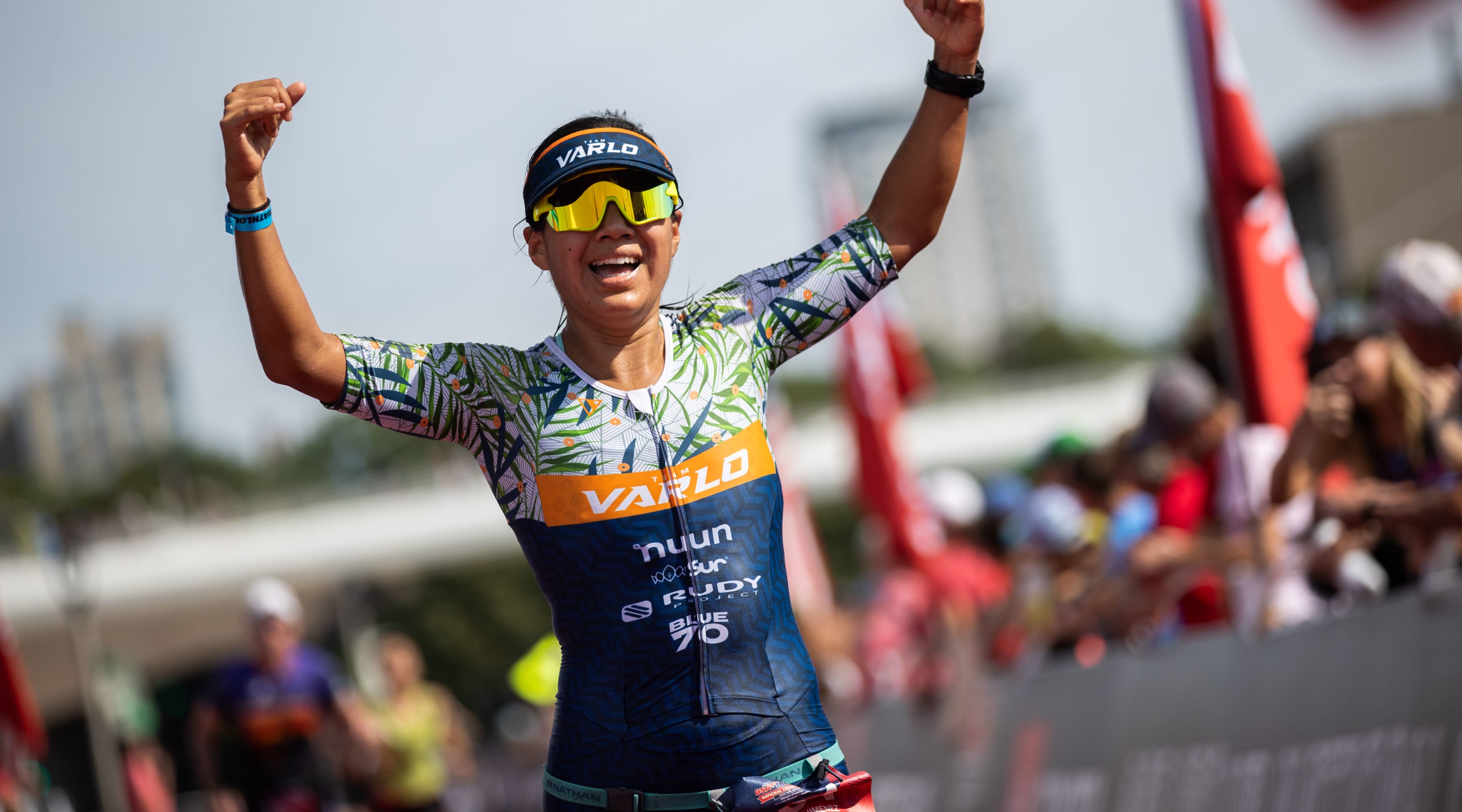 An athlete raises her arms while running down the finishing chute.