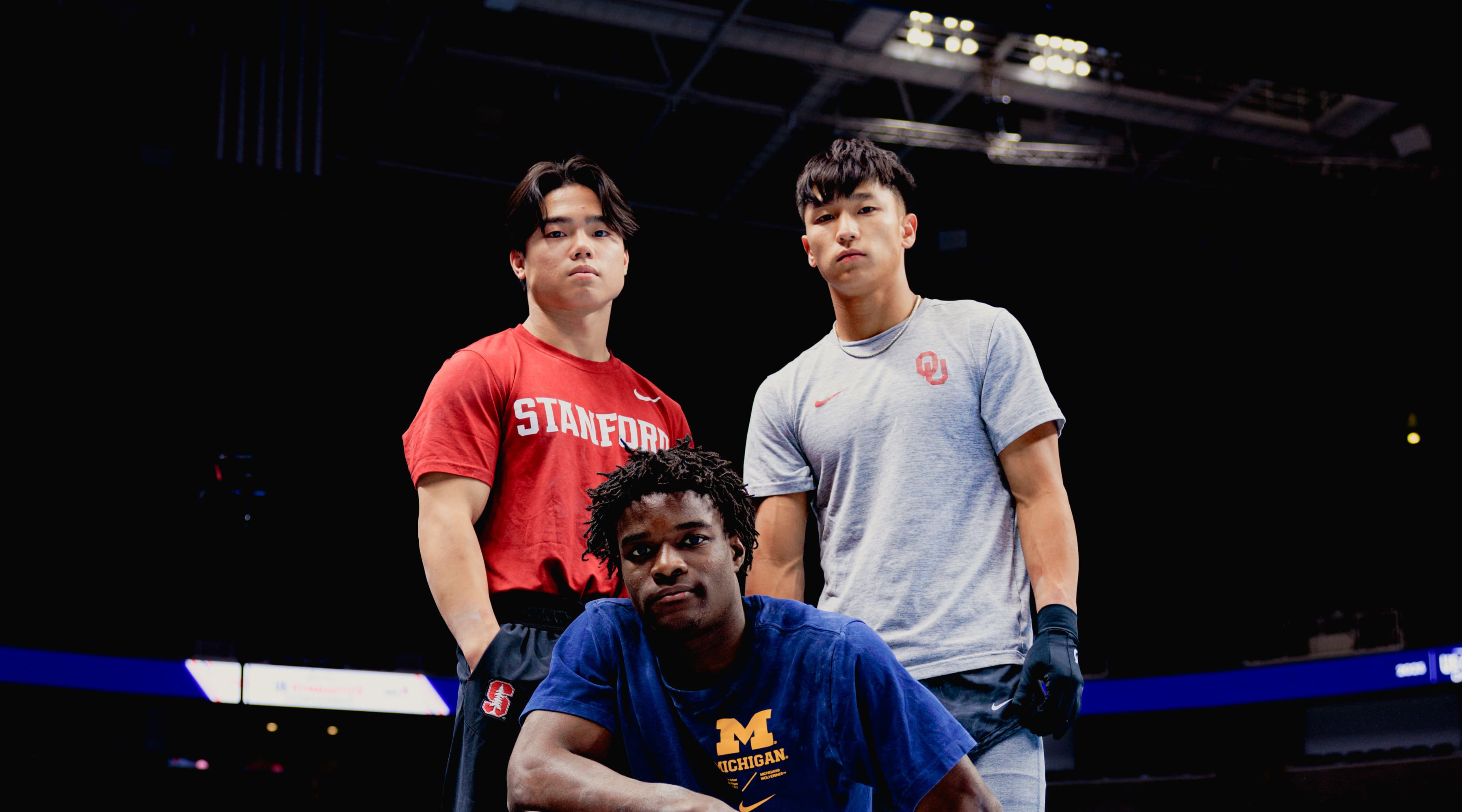 Asher Hong, Fred Richard and Yul Moldauer pose on the floor in their NCAA uniforms at the US Gymnastics Championships 2023 in San Jose, California.