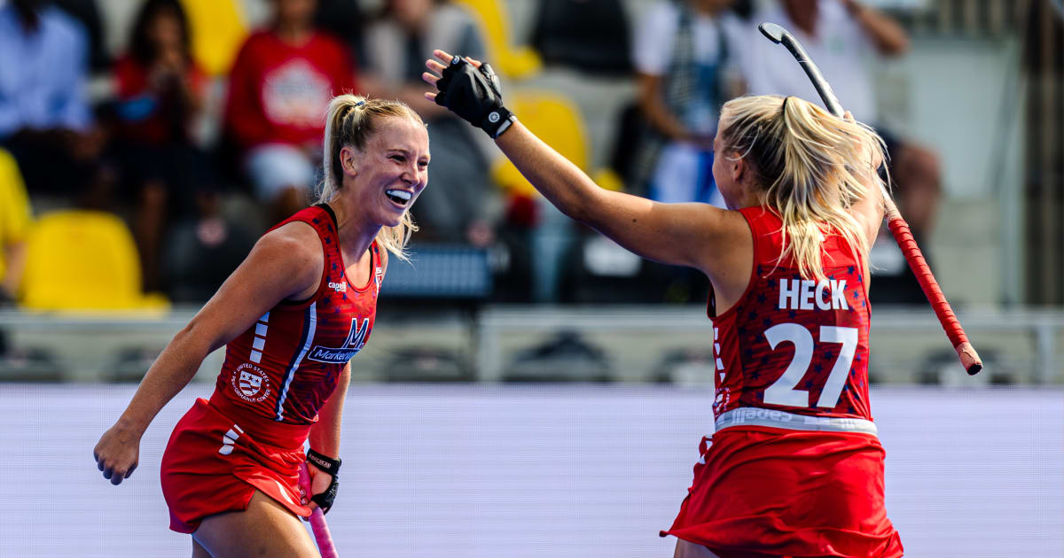 US women's field hockey players celebrating victory on field in blue uniforms