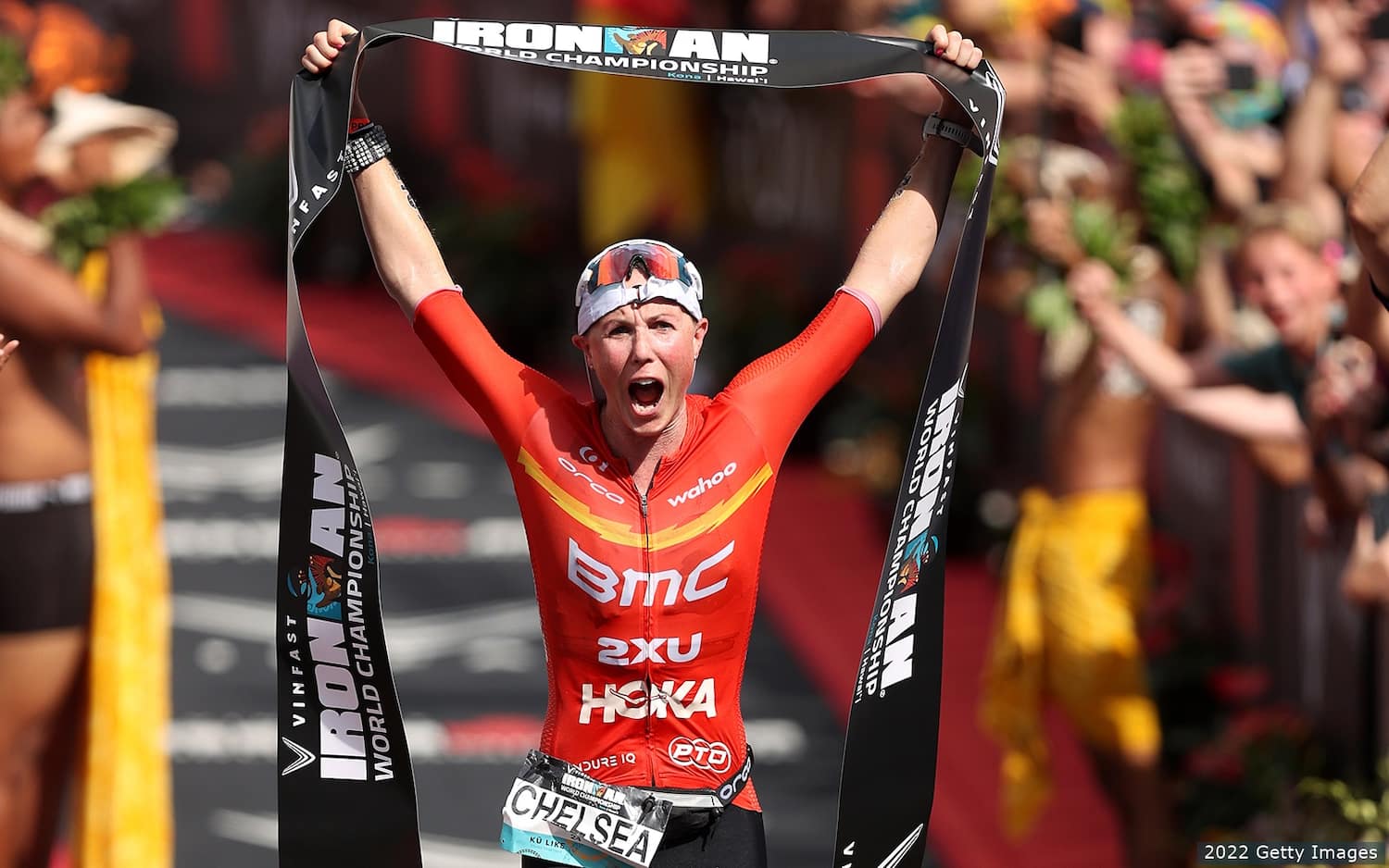 Chelsea Sodaro crosses the finish line and holds the finisher tape above her head