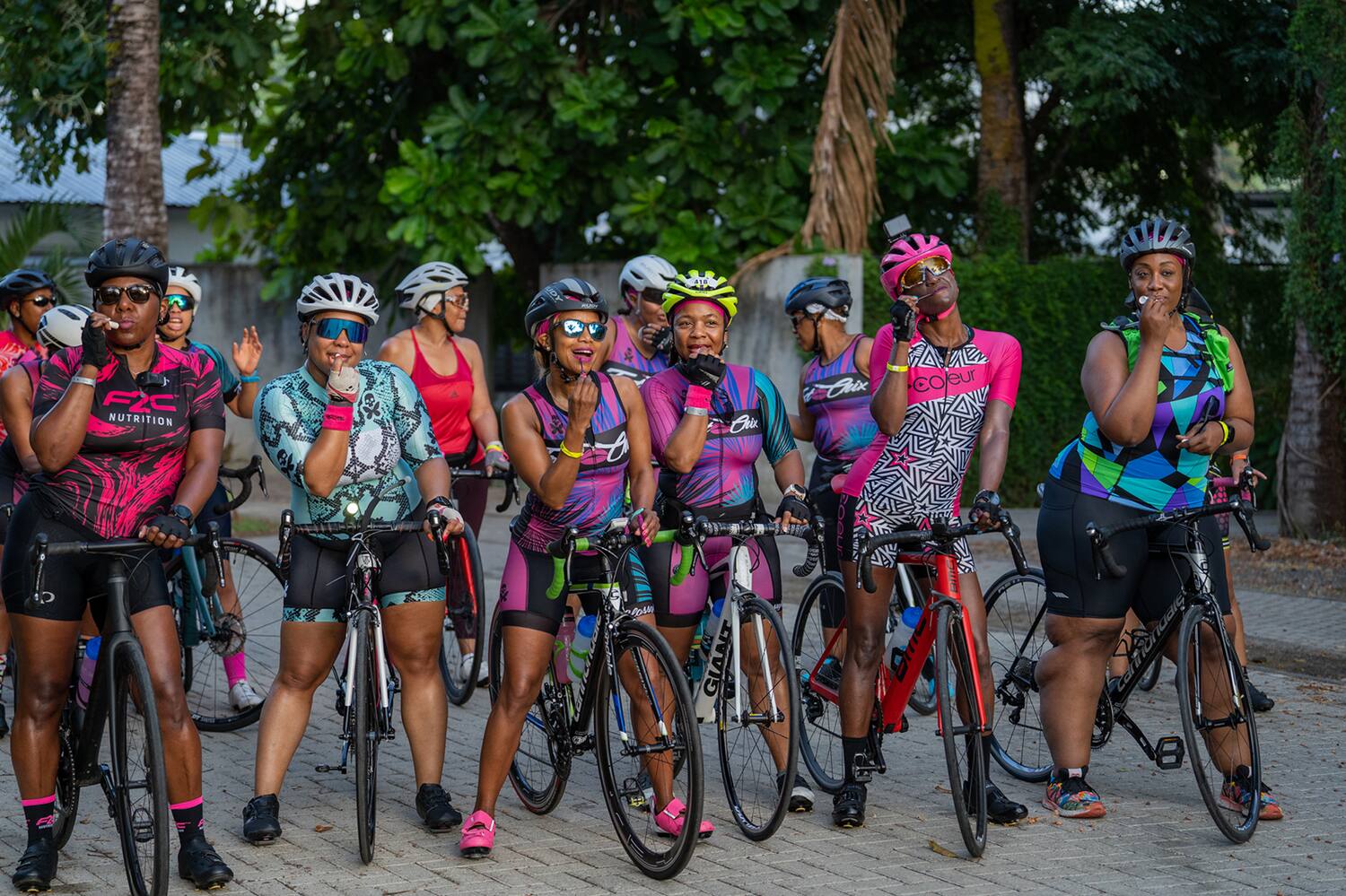 yvonne spencer and her Fast Chix triathlon club members pose for a photo while on their bikes and wearing purple tri kits