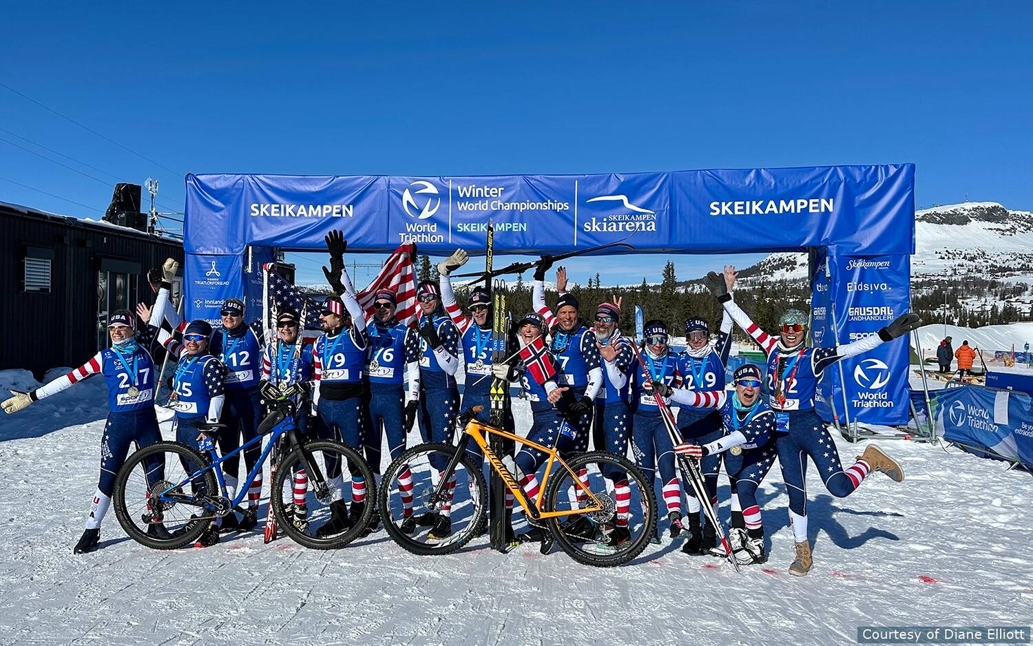 team usa poses together in front of the finish line of winter triathlon world championships