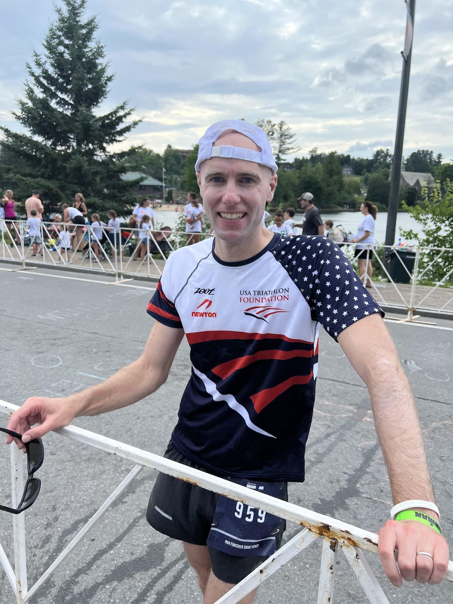 board of trustees chair Alex Egan stands near white railing, while wearing a blue, red and white USA Triathlon Foundation shirt.