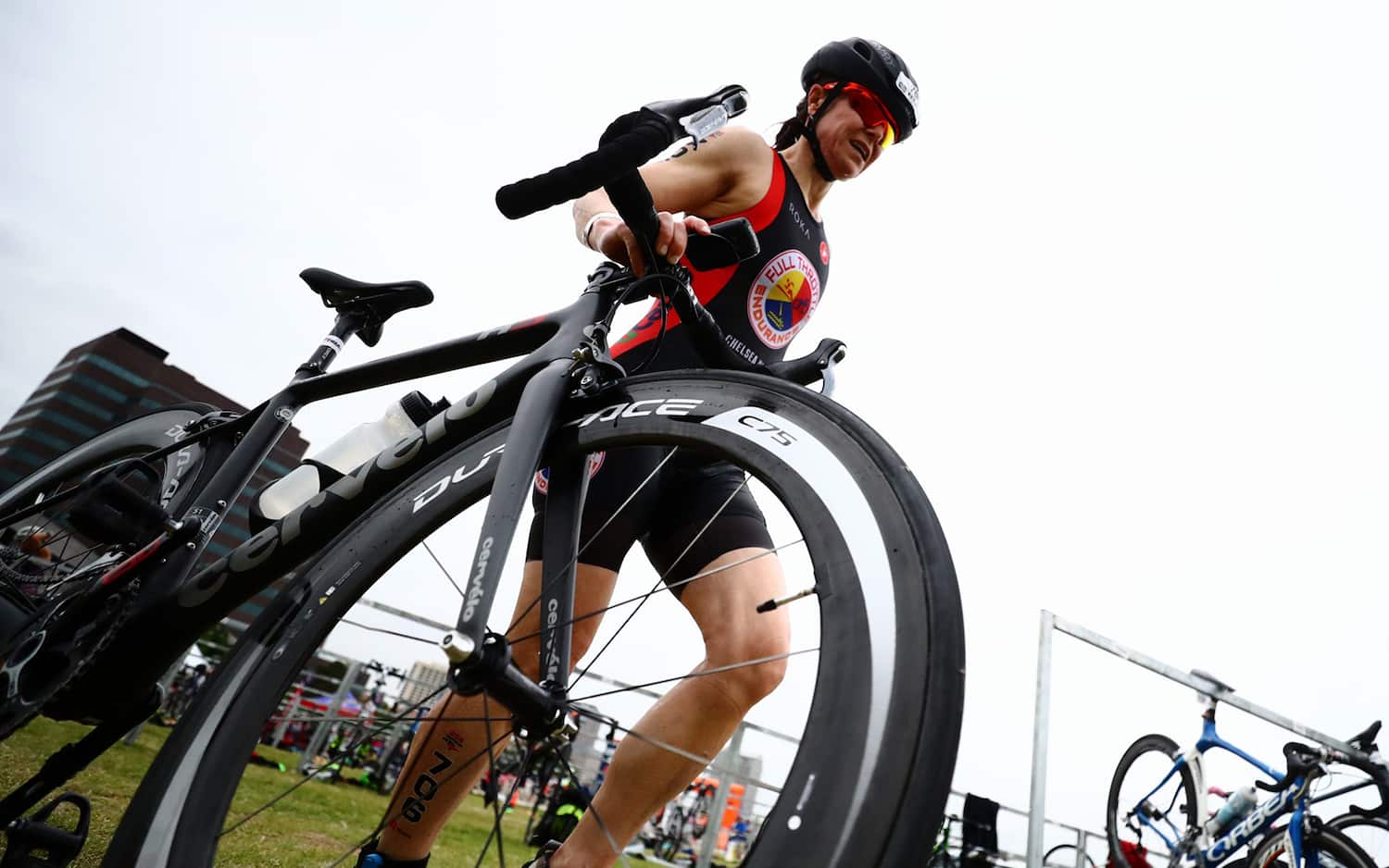 An athlete runs her bike out of the transition area at a race.