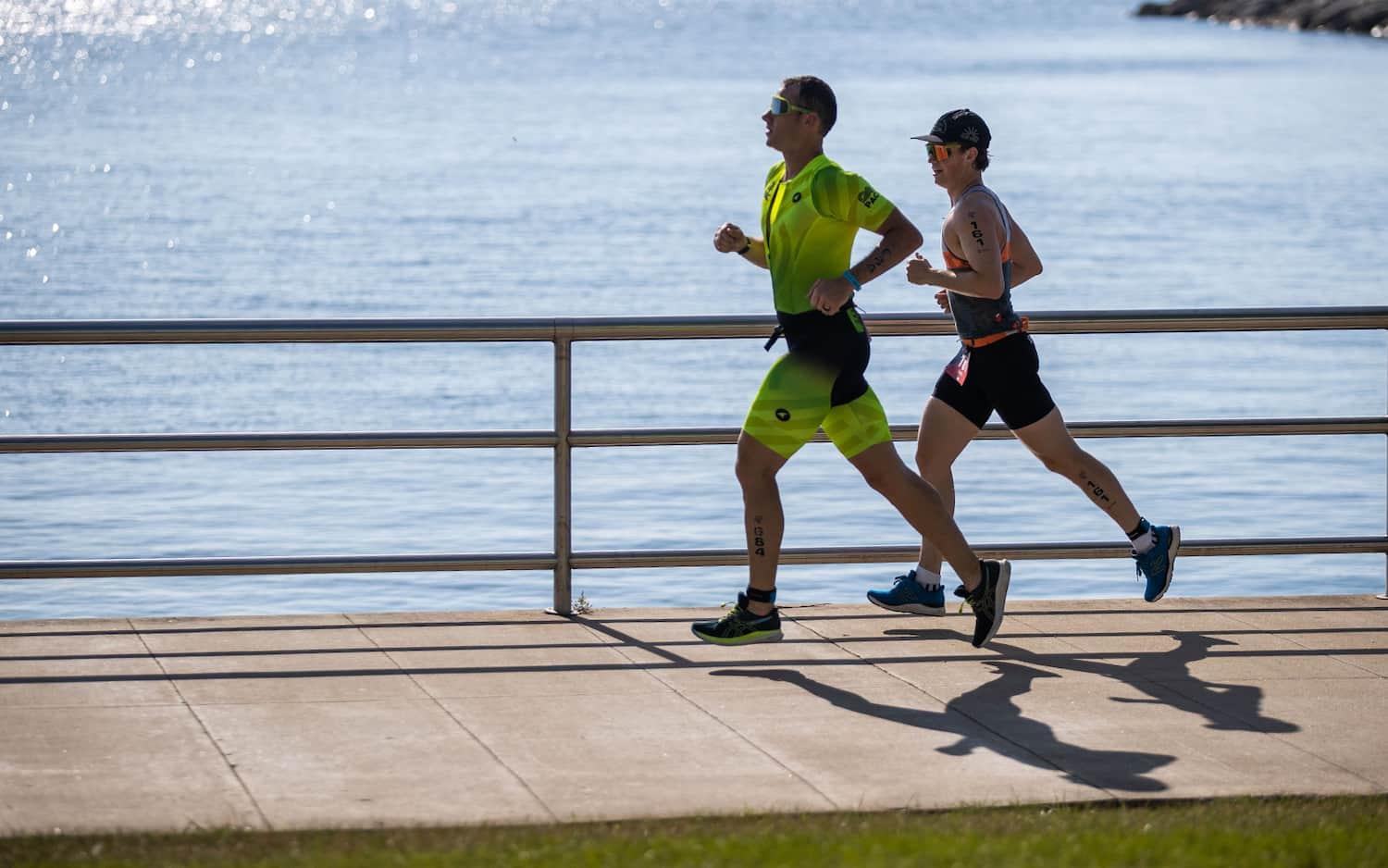 Two athletes run beside each other during the run portion of a race.