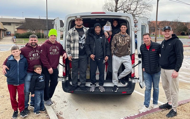 Little Rock wrestlers help fill a van with 200 donated hams.