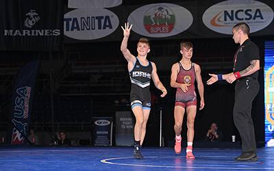 Mack Mauger of Idaho holds up four fingers after winning his Junior Greco-Roman finals to signify his four fargo titles
