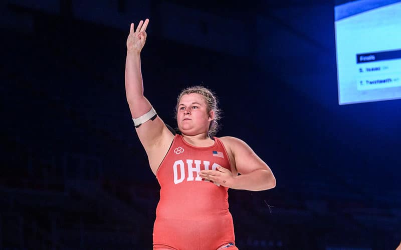 Savannah Isaac (OH) celebrates her third Fargo title by raising three fingers.