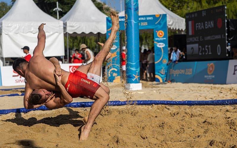 Ty Loethen (USA) tosses Peilong Li of China for a pin at 80 kg at the Beach World Series in Singapore.