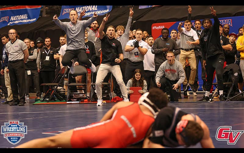 Coach Nick Mitchell (Grand View) jumps while cheering on his wrestlers.