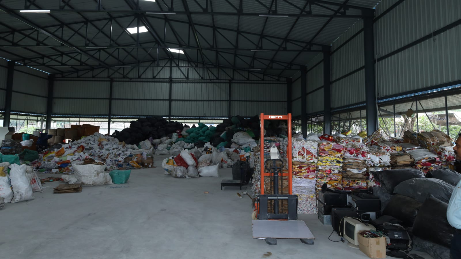 The Material Recovery Facility floor with sacks of segregated waste, a pallet stacker and recovered electronic goods