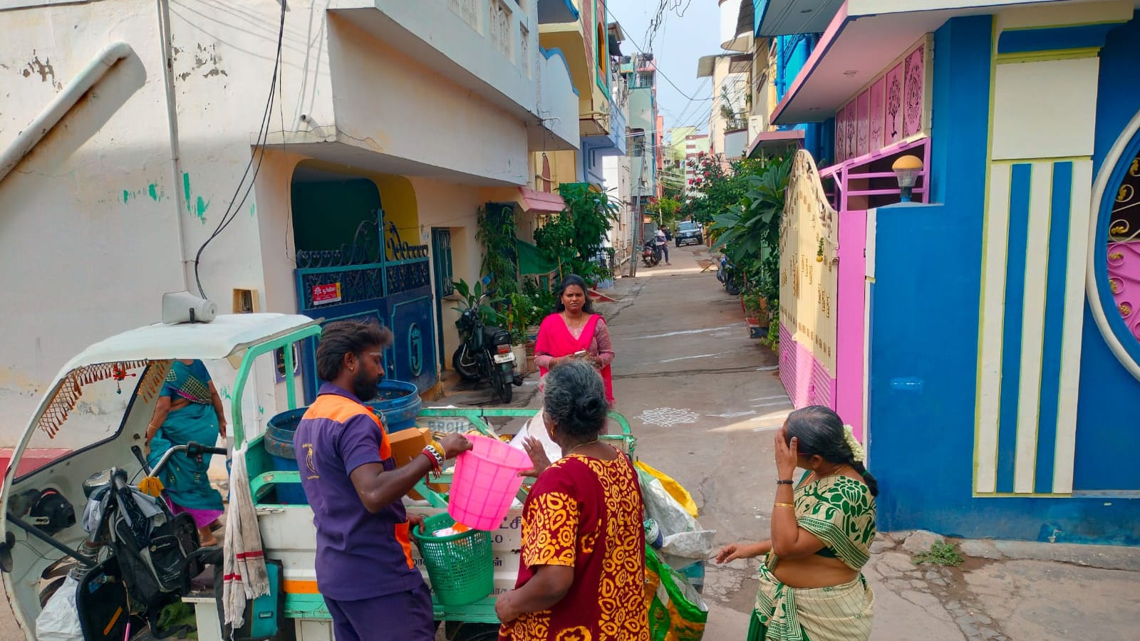 A sanitation worker collecting segregated household waste from residents at a door-to-door collection cart