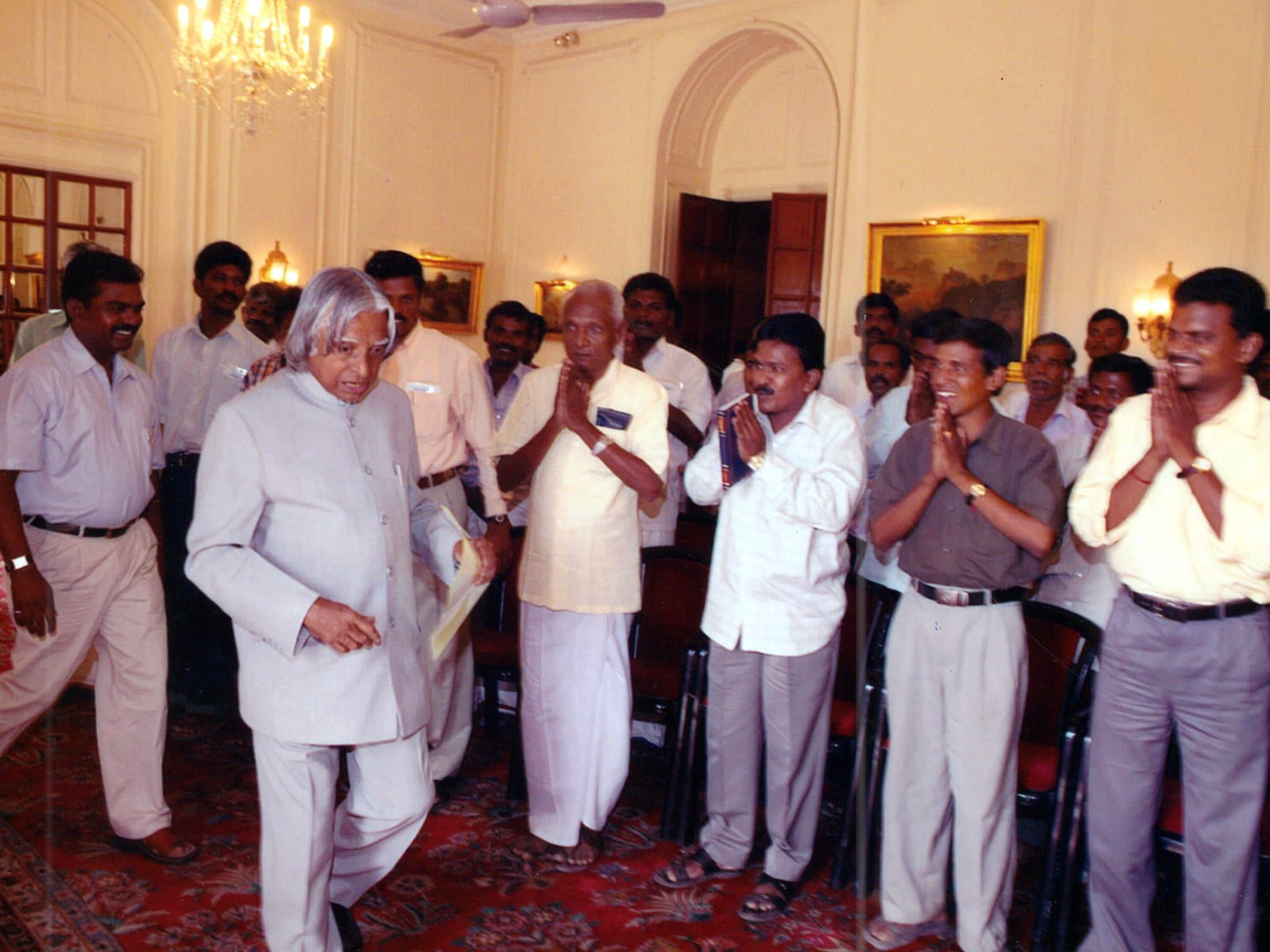 Dr. A.P.J. Abdul Kalam walking into a chandeliered reception hall past a line of visitors standing with their hands folded in greeting